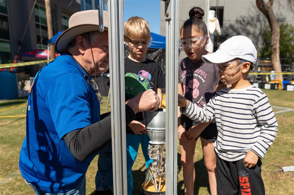 An image of an adult showing a rocket simulator to young children.